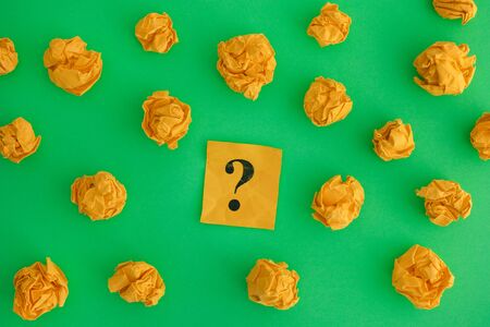 Yellow crumpled paper balls and question mark on a green background. Close up.の写真素材
