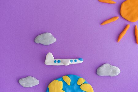 Airplane flying around the Earth. Earth, airplane and sun with clouds are made out of play clay...