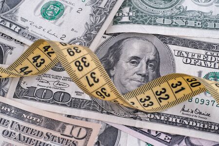 Dollar bills and yellow tape measure. Close up.の写真素材