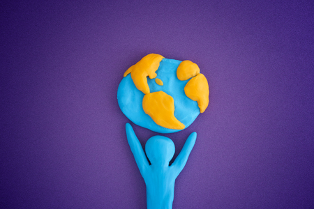 Person holding planet Earth. Person and planet Earth are made out of play clay (plasticine).の写真素材