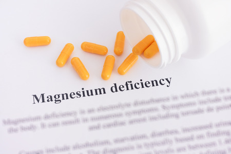 Magnesium deficiency diagnosis on paper with pills spilling out of a bottle. Close up.の写真素材