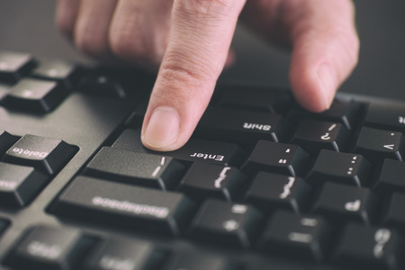 Person typing on a keyboard and pressing Enter key. Close up.の写真素材