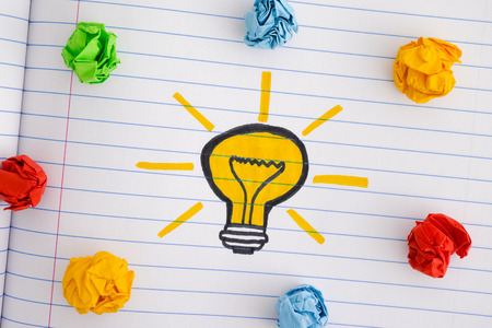 Drawing of a light bulb and colorful crumpled paper balls. New Idea Concept. Close up.