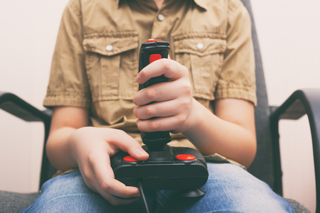 Young boy playing video game with a retro joystick. Gaming joystick from the mid-1980s. Close up.の写真素材