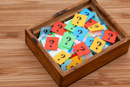 Question marks in a wooden box. Close up.