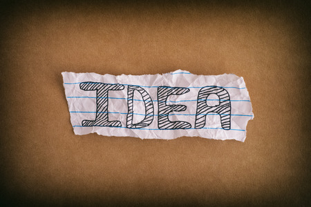 Idea. Crumpled piece of paper with the word Idea on brown paper background. Close up.の写真素材