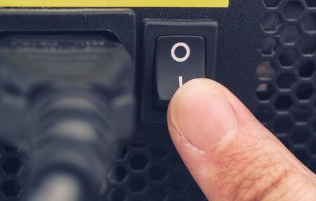 Finger switching on power supply system of PC. Close up.