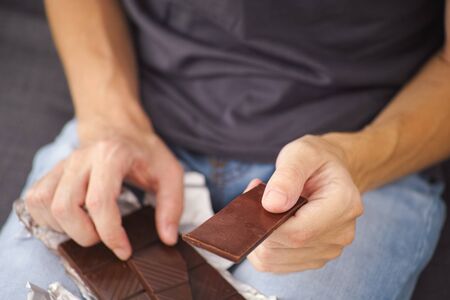 Man holding dark chocolate in his hands. Close up.