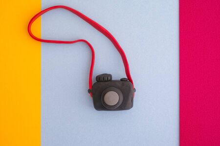 Black digital camera on a colorful background. Camera is made out of play clay (plasticine).