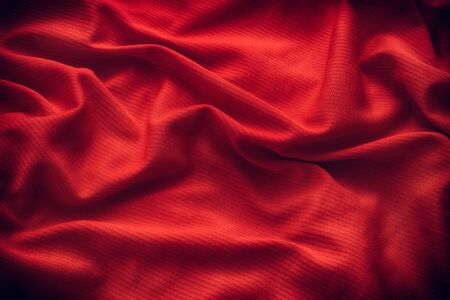 Dark red folded fabric texture background. Close up.