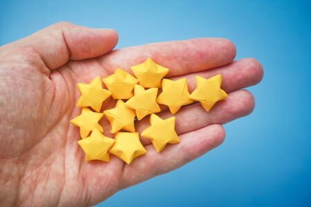 Yellow origami lucky stars in a hand. Close up.