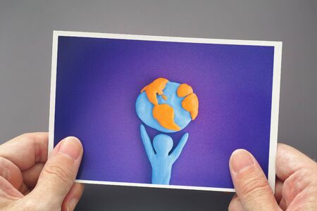 Man holding a picture with a person who is holding planet Earth. Close up.