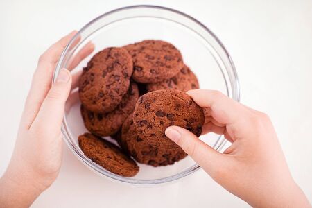 A young boy taking a homemade chocolate chip cookie from a glass bowl. Close up.