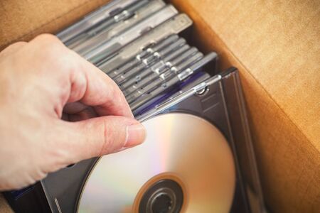 Hand taking out DVD or CD from a cardboard box.