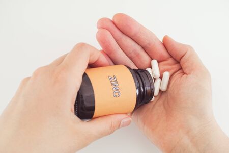 Person taking Zinc pills out of a bottle. Close up.の写真素材
