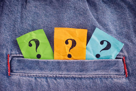 Colorful question marks sticking out of a pocket of jeans. Close up.