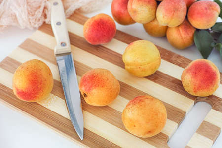 Organic apricots lying on a cutting board with a kitchen knife. Close up.の写真素材
