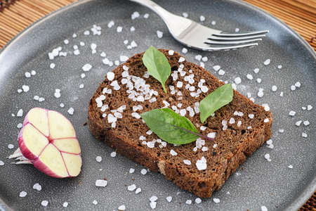 Whole grain organic bread with sea salt and basil leaves. Close up.