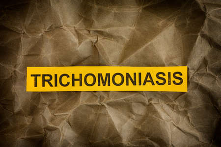 Trichomoniasis. Yellow piece of paper with the word Trichomoniasis. Close up.