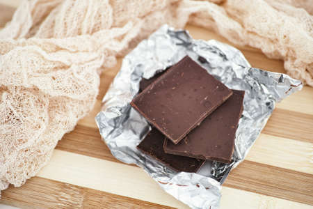 Pieces of dark broken chocolate in wrapping foil. Close up.