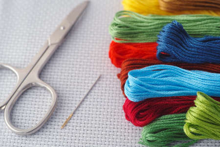 Colorful cross stitch embroidery threads with needle and scissors. Close up.の写真素材