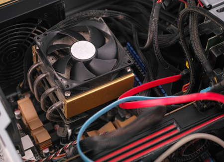 CPU fan with dust inside of a PC computer case with poor cable management. Close up.