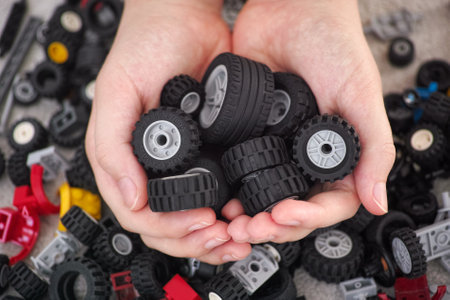 Tambov, Russian Federation - March 11, 2021 A young boy holding a handful of Lego wheels in his hands.のeditorial素材