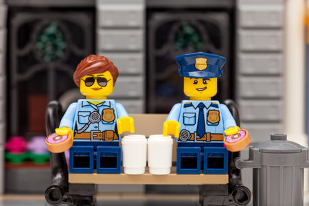 Tambov, Russian Federation - March 19, 2021 Lego policeman and policewoman minifigures sitting on a bench and drinking coffee and eating donuts.のeditorial素材