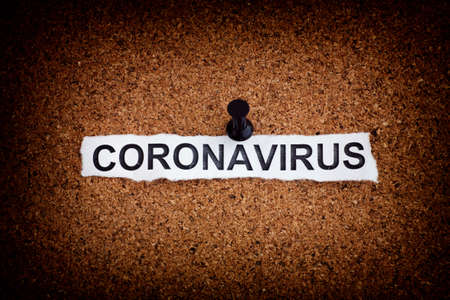 Coronavirus. Torn piece of paper with the word Coronavirus on a cork board. Close up.の写真素材