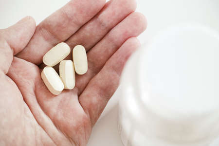 A man holding magnesium taurate tablets in his hand. Close up.