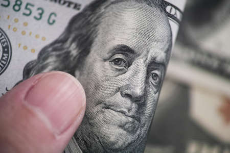 A man holding a one hundred dollar bill in his hand. Close up.