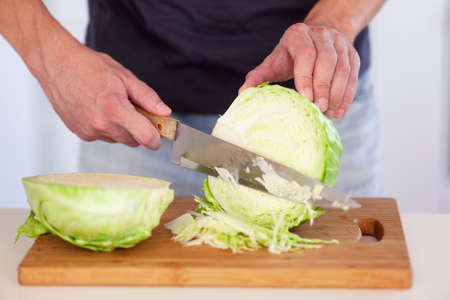 A man cutting a cabbage on a cutting board. Close up.の写真素材