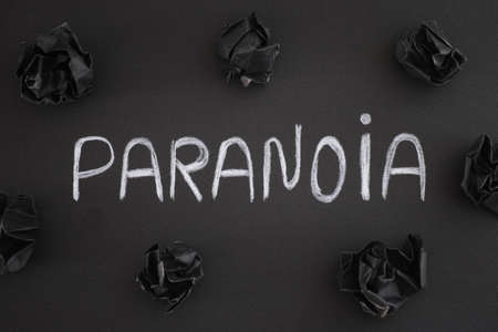 The word Paranoia on a black background with black crumpled paper balls around it. Close up.の写真素材