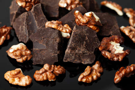 Broken organic homemade dark chocolate with walnuts around it. Close-up.の写真素材