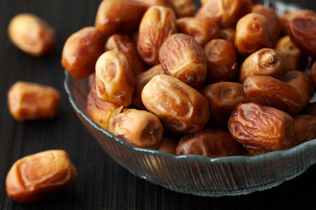 Dried dates in a glass bowl. Low key. Close up.の写真素材