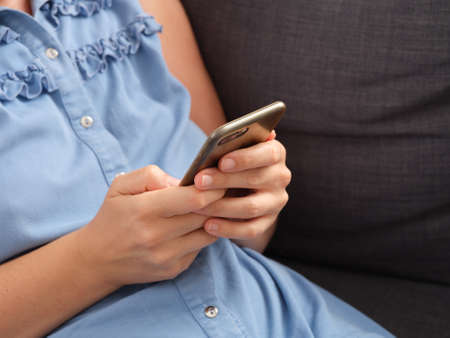 A woman using a smartphone while sitting on a couch. Close up.