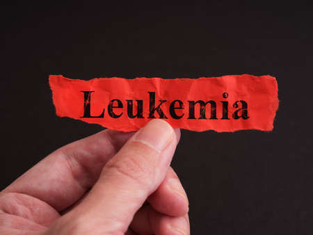 A man holding a piece of red paper with the word Leukemia on it. Close up.の写真素材