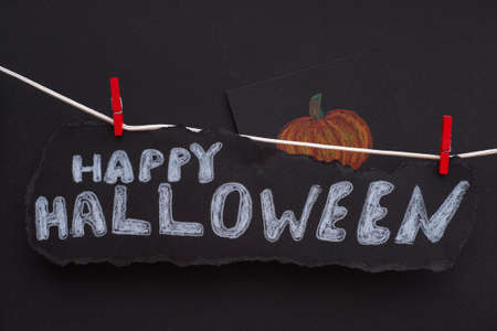 The words Happy Halloween on a black piece of paper hanging on a clothes line. Black Background. Close up.の写真素材