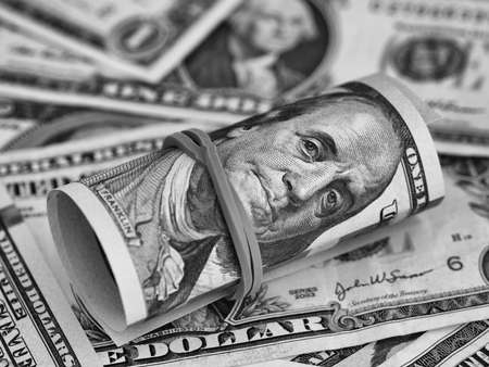 A tied stack of one hundred dollar bills on a dollar bill background. Black and white. Close upの写真素材