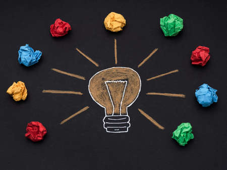 A drawing of a light bulb with colorful crumpled paper balls around it. Close up.の写真素材
