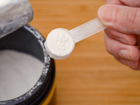 A man holding a scoop of AAKG powder in his hand. AAKG supplement. Close up.の写真素材