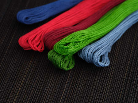 Colorful cross stitch embroidery threads on a black background. Close up.