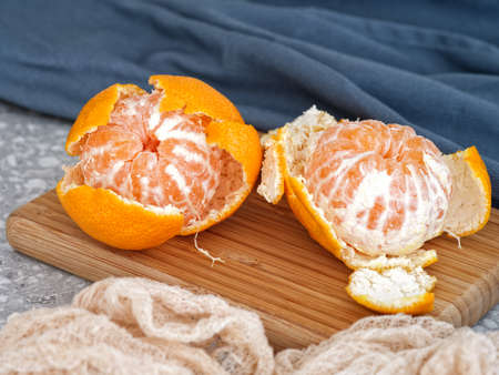 Two peeled tangerines on a cutting board that is on a countertop. Close up.