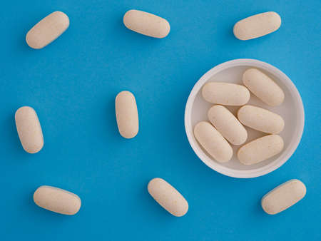 Magnesium Taurate tablets in a cap with other magnesium taurate tablets around them. close up.