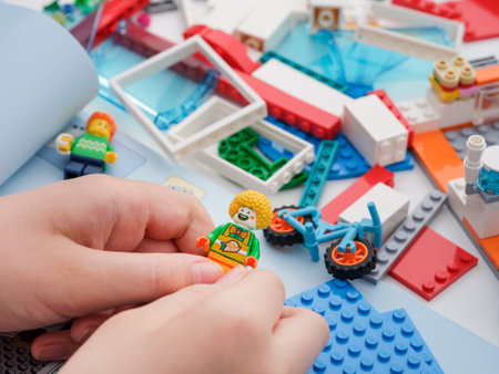Tambov, Russian Federation - February 09, 2022 A child holding a lego clown minifigure while building a Lego set. close up.のeditorial素材