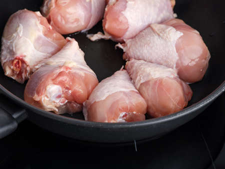Chicken drumsticks in a frying pan ready to be cooked. low key. close up.の写真素材