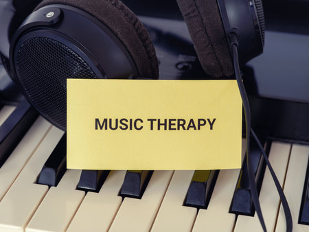 A yellow paper note with the words Music Therapy lying on a piano with headphones behind it. Close up.の写真素材