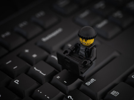 Tambov, Russian Federation - August 25, 2022 A Lego robber minifigure sitting on a computer keyboard and hacking a network with a laptop.のeditorial素材
