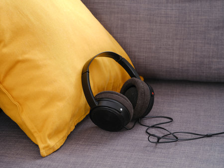 Headphones on a gray couch with yellow cushion. Close up.の写真素材