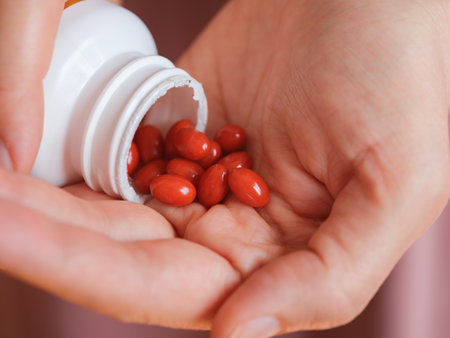 A woman pouring Lutein softgels out of a bottle into the palm of her hand. Close up.